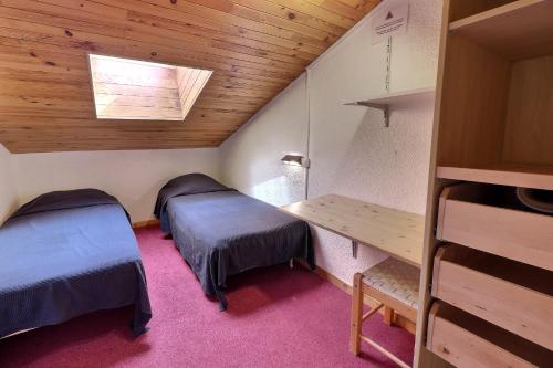 Habitación pequeña con 2 camas y mesa. en Residence Saulire, en Méribel