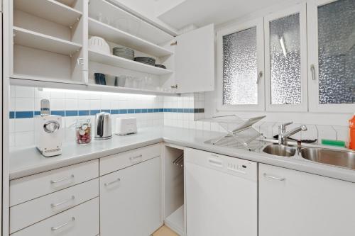 una cocina blanca con armarios blancos y fregadero en Spacious Central Apartments HOTING, en Zúrich