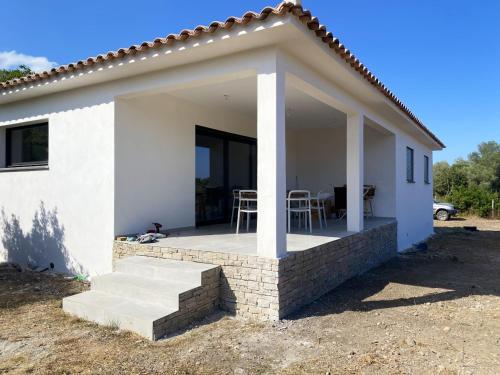 a white house with a porch with a table and chairs at Maison chaleureuse à Serra-Di-Fiumorbo in Serracinella