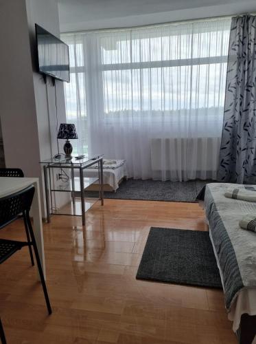 a living room with a table and a large window at Figaro Apartaments in Gdynia