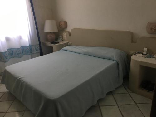 1 dormitorio con cama y ventana en green park cala di volpe en Abbiadori