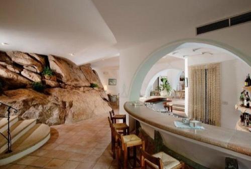 een kamer met een rotswand en een badkamer met surfplanken bij green park cala di volpe in Abbiadori