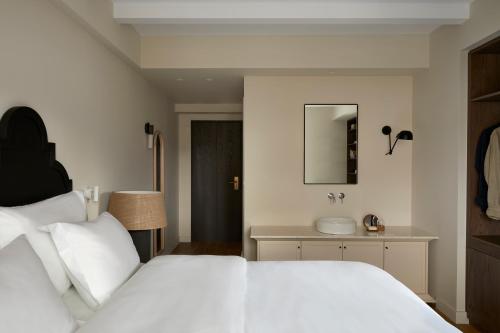 a bedroom with a white bed and a sink at The Storyteller Boutique House in Kalabaka