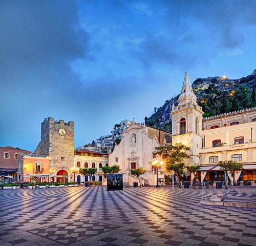 una piazza cittadina con un edificio e una torre dell'orologio di Al Teatro Antico Rooms & House a Taormina