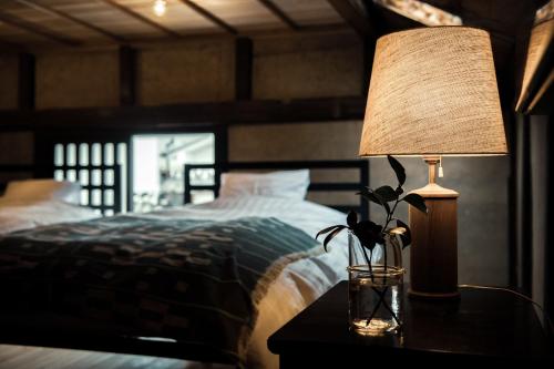 ein Schlafzimmer mit einem Bett und einer Lampe auf einem Tisch in der Unterkunft Oito 美しい街並みに佇む喫茶と宿 in Tamba-sasayama