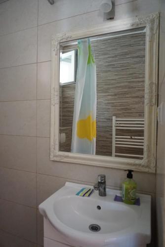 baño con lavabo, espejo y ventana en Pensiunea Elias, en Cluj-Napoca