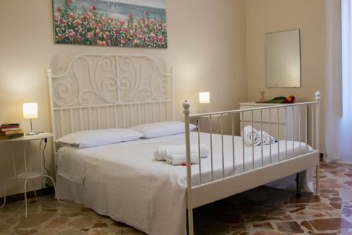 een slaapkamer met een wit bed en een schilderij aan de muur bij La Casa della Nonna in San Mauro Castelverde