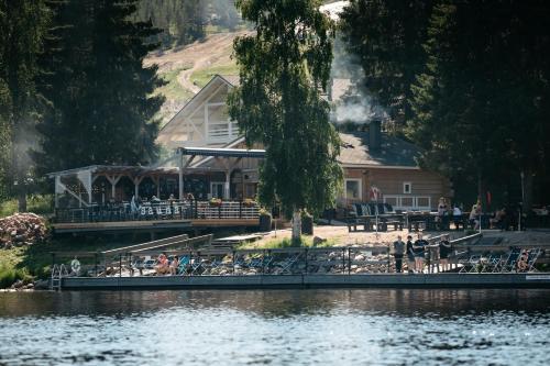a group of people sitting on a dock next to a lake at Lapland Hotels Ounasvaara Chalets in Rovaniemi
