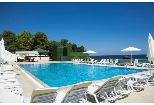 Westport Istanbul Resort & Spa Hotel في سيليفري: مسبح كبير وكراسي بيضاء ومظلات