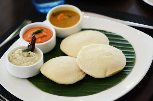 a plate of food with some dipping sauces and biscuits at Ethnotel, Kolkata Airport in Kolkata