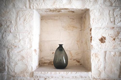 a black vase sitting on a shelf in a brick wall at Dimorae Camà in Cisternino
