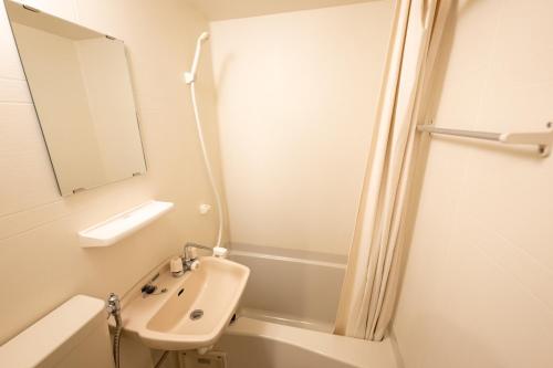 Baño blanco con lavabo y espejo en Hotel Ekichika Nagahoribashi, en Osaka