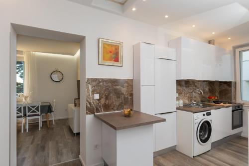 una cucina con armadi bianchi e una lavatrice/asciugatrice di D Place a Dubrovnik