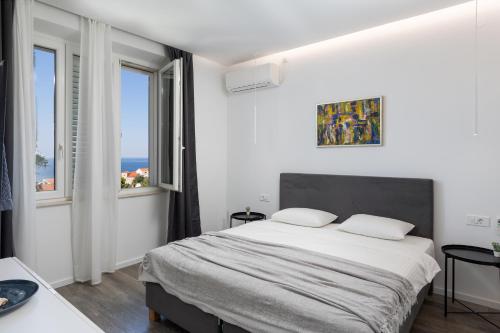 a white bedroom with a large bed and two windows at D Place in Dubrovnik