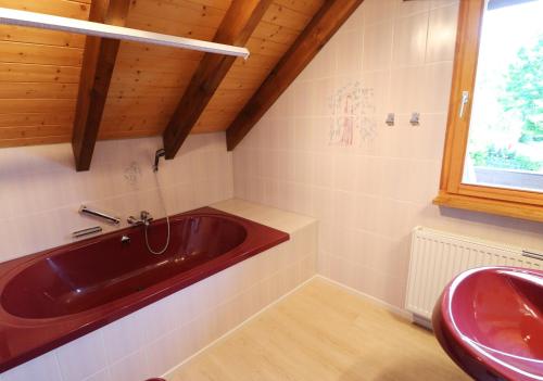 ein Badezimmer mit einer roten Badewanne und einem Waschbecken in der Unterkunft Haus Panoramablick - Fewo Alpenblick, Höchenschwand in Höchenschwand
