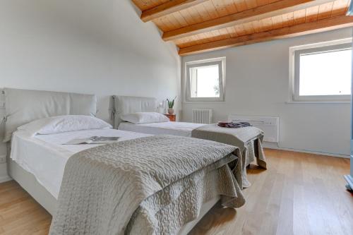 シローロにあるIl Vigneto di Montefreddo- My Extra Homeの白い壁と木製の天井が特徴の客室で、ベッド2台が備わります。
