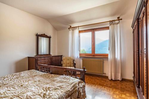 a bedroom with a bed and a mirror and a window at La finestra sul Lago Tenna Ospitar in Tenna 