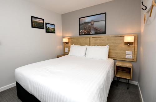a hotel room with a large bed and two pictures on the wall at Fox & Goose, Barrow Gurney by Marston's Inns in Bristol