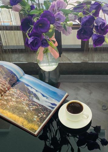 a table with a cup of coffee and a book and flowers at Har-Mar Hotel in Goris