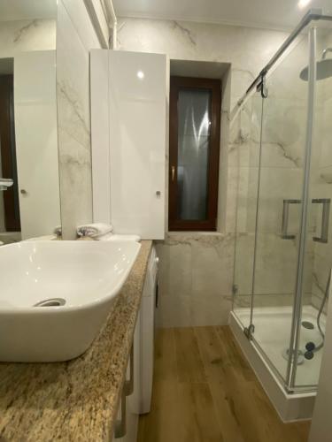 a white bathroom with a sink and a shower at Intimate Inn in Arad