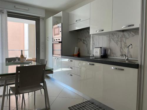 a kitchen with white cabinets and a table and chairs at West bay in Menton
