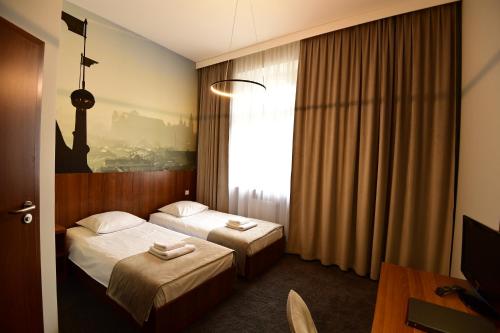 a hotel room with two beds and a window at Hotel Downtown Kraków in Kraków