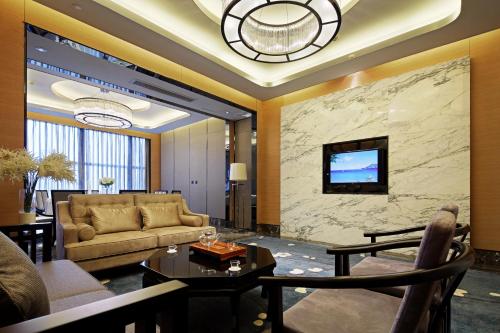 a living room with a couch and a tv on a wall at Ramada Changzhou North Hotel in Changzhou
