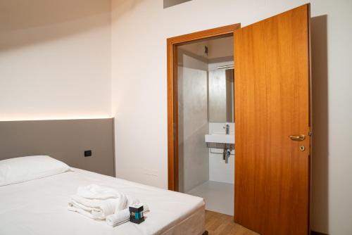 Schlafzimmer mit einem Bett mit weißer Bettwäsche und einer Holztür in der Unterkunft Gustificio in Carmignano di Brenta