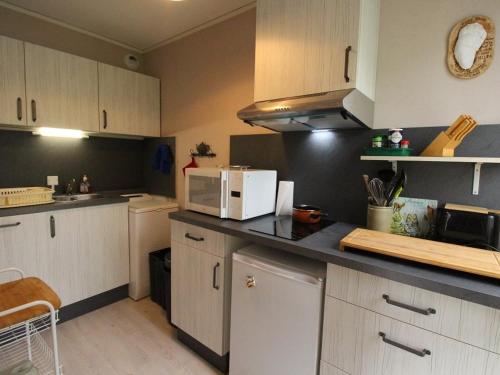 une cuisine avec des armoires blanches et un micro-ondes dans l'établissement Charmant T2 avec balcon, parking privé, au pied du télécabine - Bagnères-de-Luchon - FR-1-313-198, à Luchon