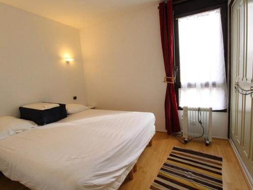 une chambre avec un lit blanc et une fenêtre dans l'établissement Charmant T2 avec balcon, parking privé, au pied du télécabine - Bagnères-de-Luchon - FR-1-313-198, à Luchon