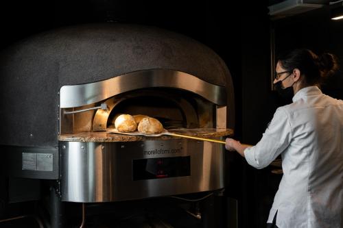 a woman is putting food into an oven at Gustificio in Carmignano di Brenta