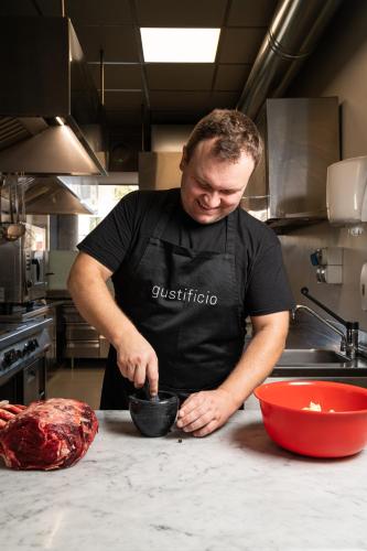 a man in a kitchen preparing food in a bowl at Gustificio in Carmignano di Brenta