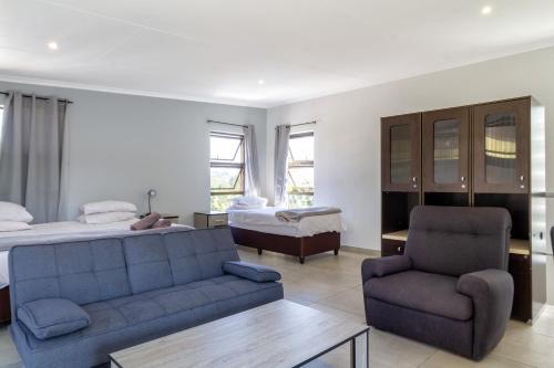 a bedroom with a couch and a bed and a chair at Linden Guest House in Johannesburg