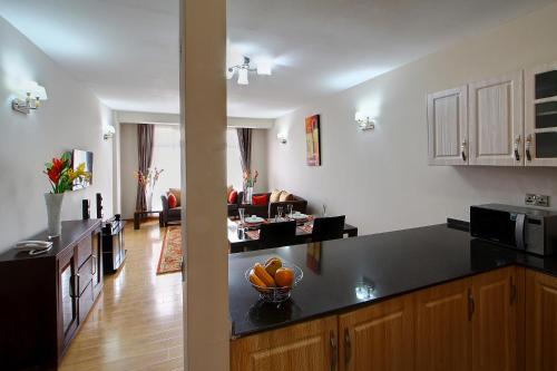 a kitchen with a counter top and a living room at Fenesi Gardens Apartments in Nairobi