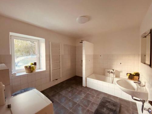 La salle de bains blanche est pourvue d'une baignoire et d'un lavabo. dans l'établissement Ferienwohnung Nennigmühle, 