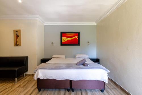 a bedroom with a bed and a chair at Linden Guest House in Johannesburg