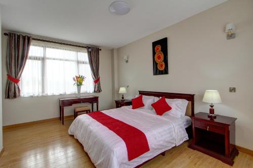 a bedroom with a bed and two tables and a window at Fenesi Gardens Apartments in Nairobi