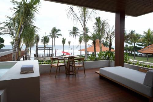 a room with a bed and a table with a view of the ocean at Amarta Beach Retreat by Nakula in Tabanan