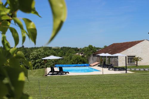 une piscine avec chaises et parasols dans une cour dans l'établissement Aux Vents d'anges, à Cahuzac-sur-Vère