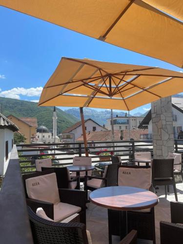 a patio with tables and chairs and a large umbrella at Kula Nekovic in Gusinje