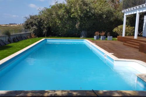 una piscina en un patio trasero con terraza de madera en Gorgeous Mansion by Caesarea's Greatest Beach-hosted by Sweetstay, en Cesarea