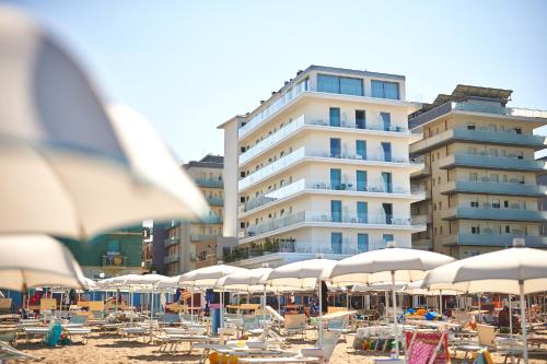 une plage avec des chaises et des parasols et un grand bâtiment dans l'établissement Hotel delle Nazioni, à Pesaro