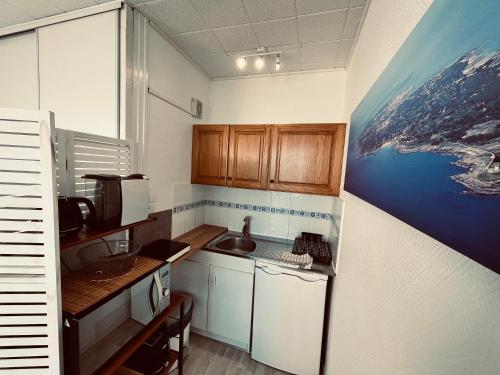 une petite cuisine avec un tableau sur le mur dans l'établissement Studio panoramique océan du Marina, à Saint-Jean-de-Monts