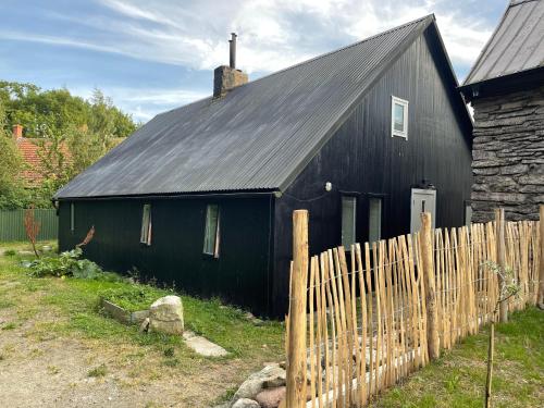 a black barn with a black roof and a fence at Two Bedroom, Newly Renovated, Garden Apartment in Gärsnäs, Österlen in Gärsnäs