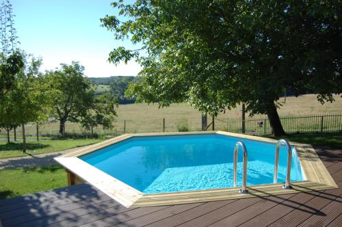 uma piscina num deque com vista para um campo em La Petite Maison em Campsegret