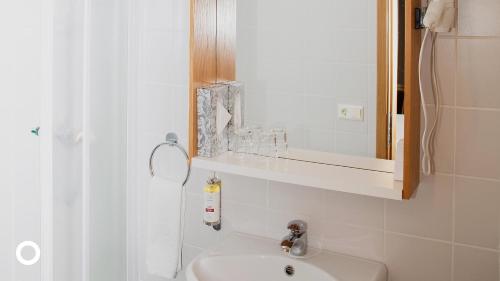 ein weißes Badezimmer mit einem Waschbecken und einem Spiegel in der Unterkunft Center Hotels Skjaldbreid in Reykjavík