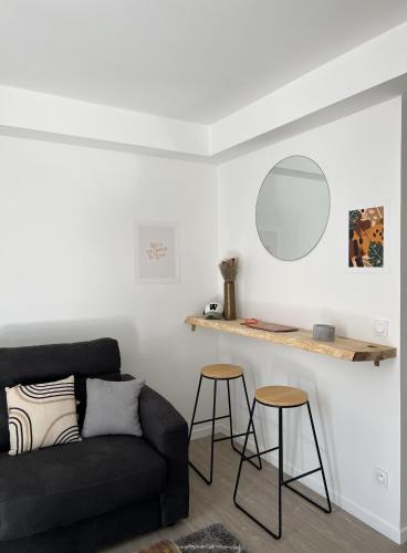 ein Wohnzimmer mit einer Couch und zwei Hockern in der Unterkunft Appartement situé en plein coeur du centre-ville in Rochefort