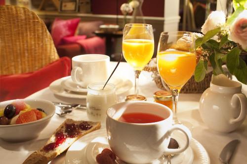 een tafel met een kopje thee en twee glazen sinaasappelsap bij Hôtel Sainte-Beuve in Parijs