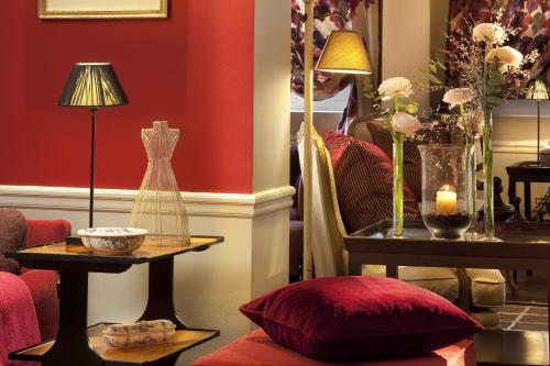 a living room with red walls and a table with a red pillow at H&ocirc;tel Sainte-Beuve in Paris