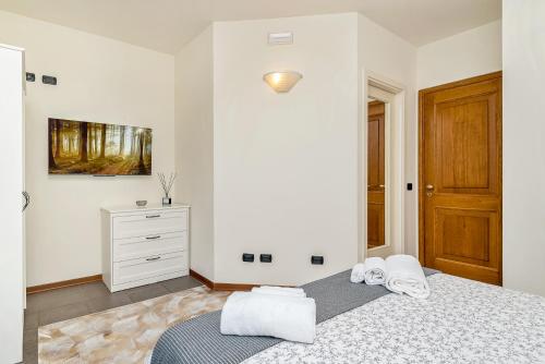 a white bedroom with a bed and a dresser at Hotel la Pietra restaurant in Fosdinovo